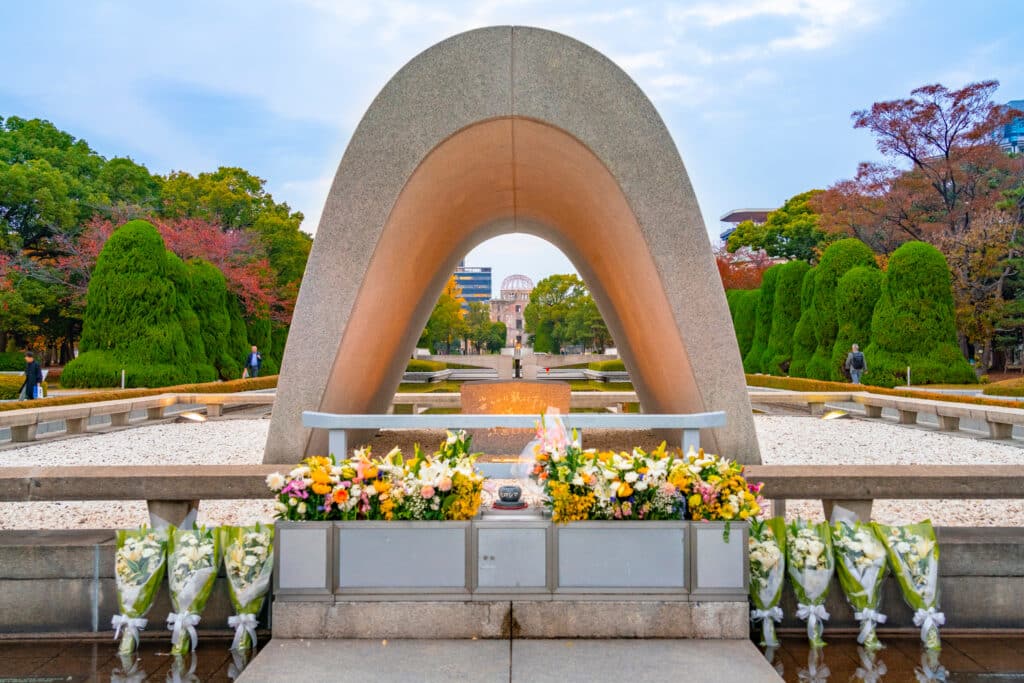 Hiroshima Peace Memorial Cenotaph with flowers and Atomic Bomb Dome in background