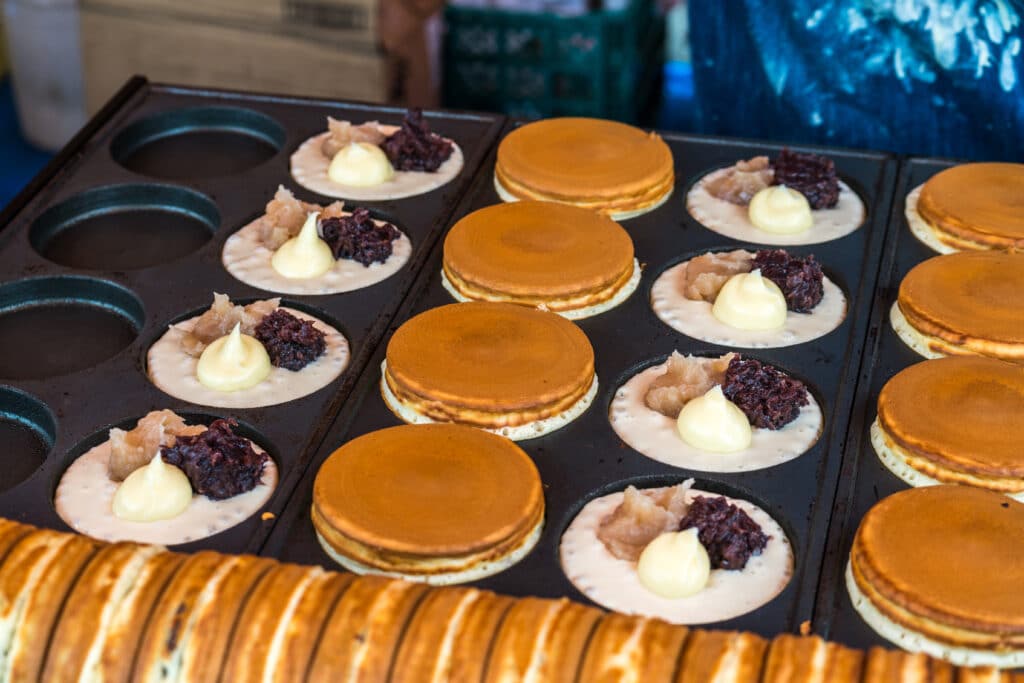 Imagawayaki filled with red bean paste and custard cooking on a griddle