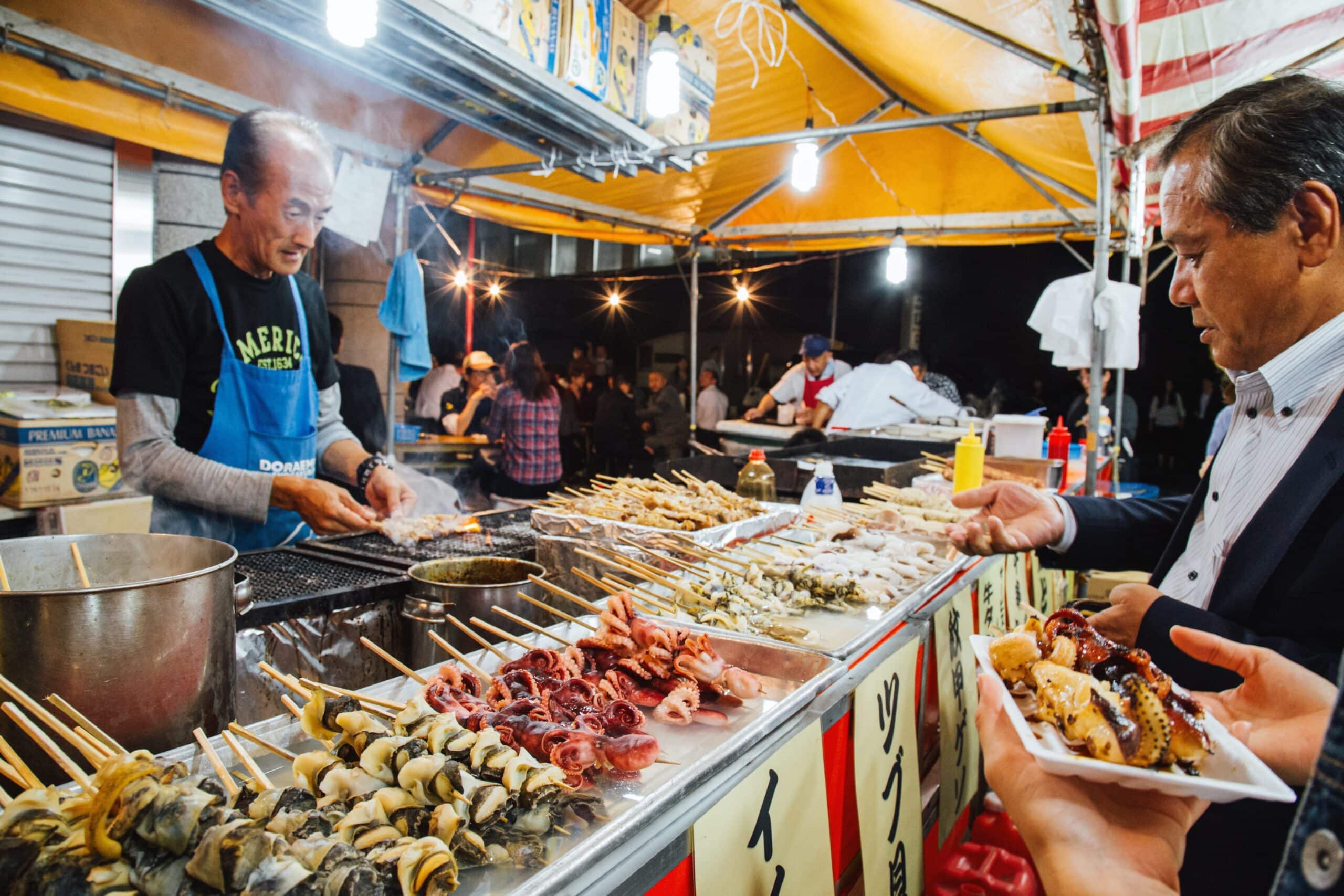 Japanese seafood street food stall with grilled skewers at a night festival