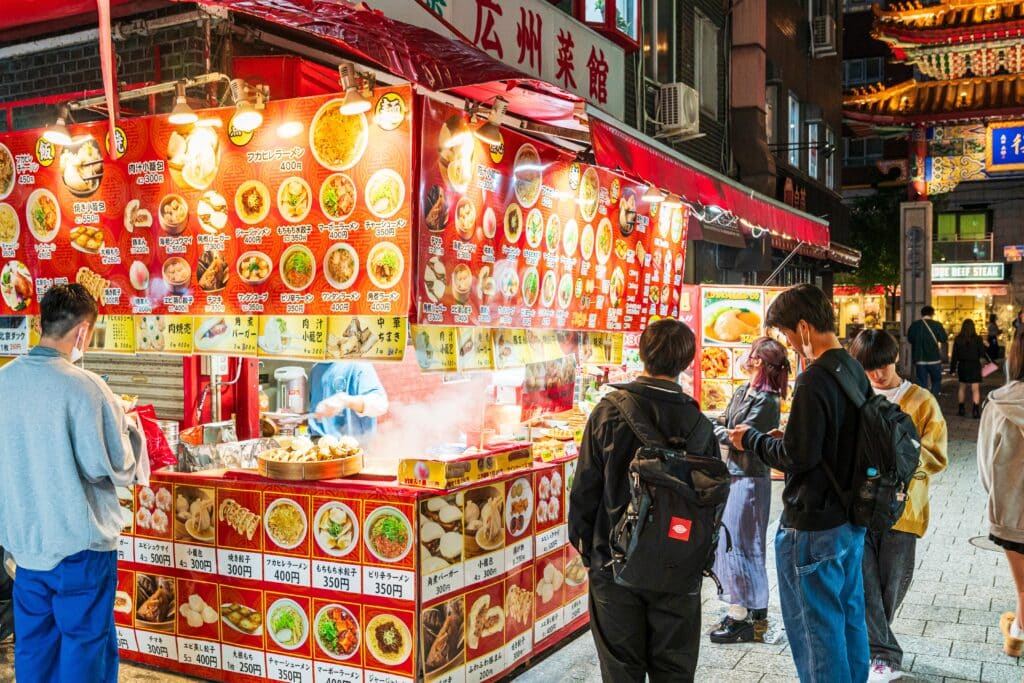 Japanese street food stall at night with colorful menu signs and customers