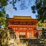 Entrance gate of Kasuga Taisha shrine in Nara surrounded by stone lanterns and forest