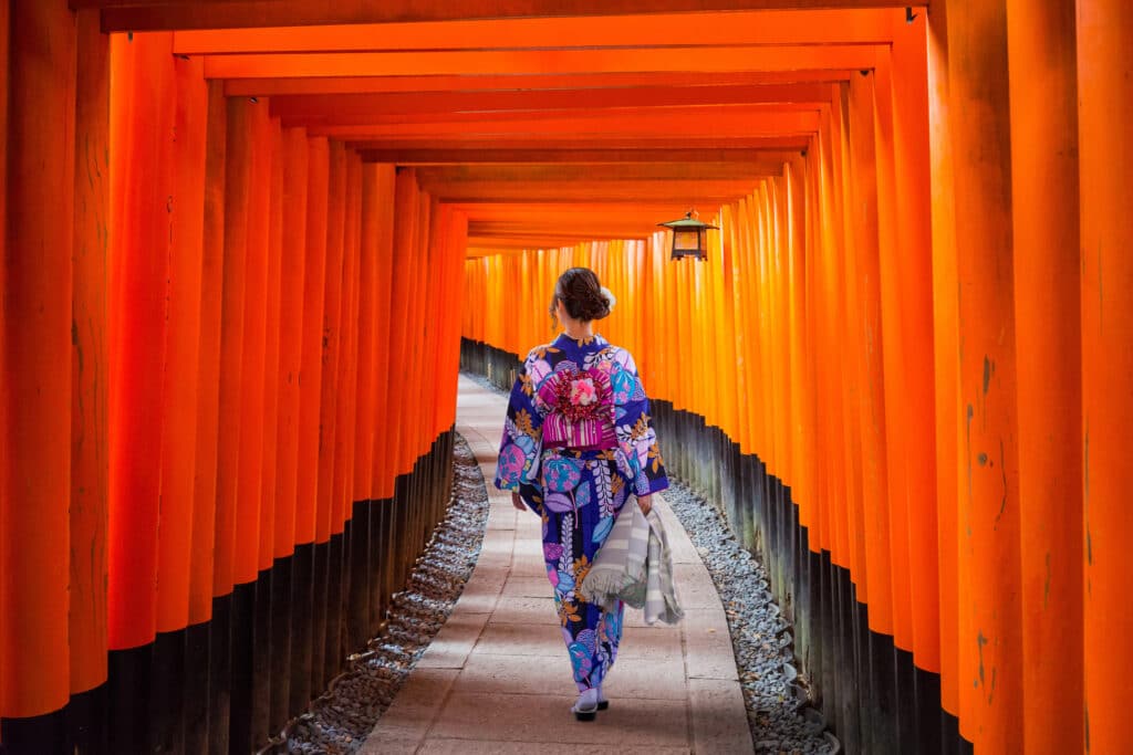 Traveler walking through the red torii gates at Fushimi Inari Shrine in Kyoto