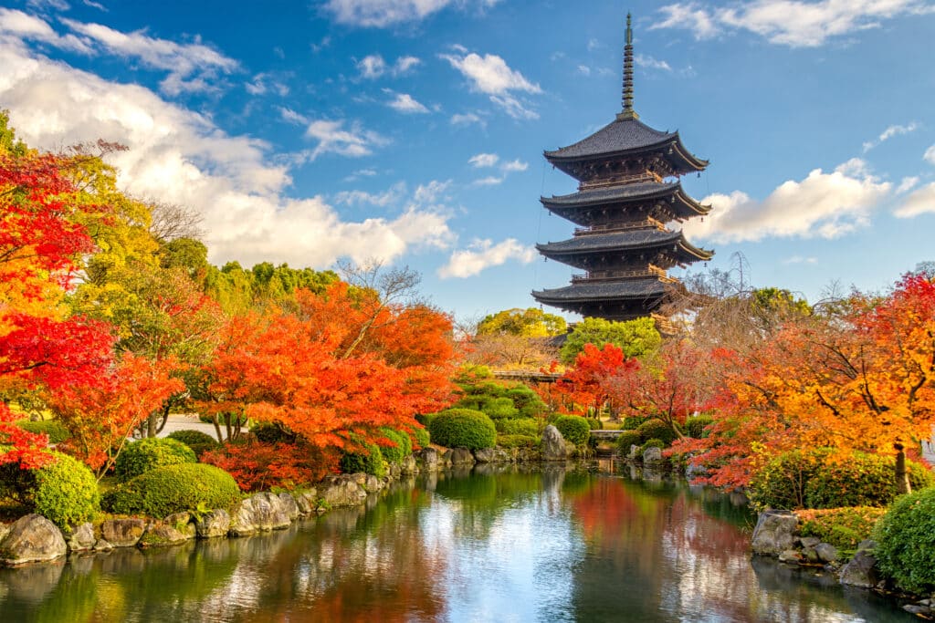 five story pagoda in Kyoto with autumn foliage and pond reflection