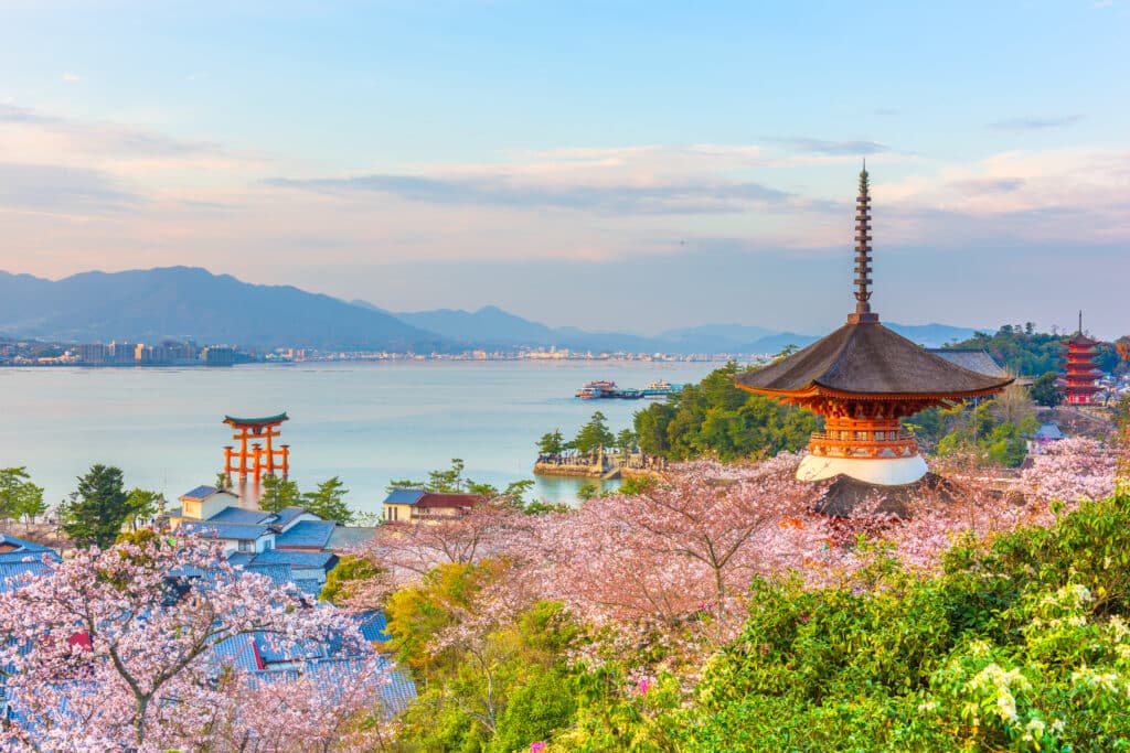View of Miyajima island with pagoda, cherry blossoms, and floating torii gate