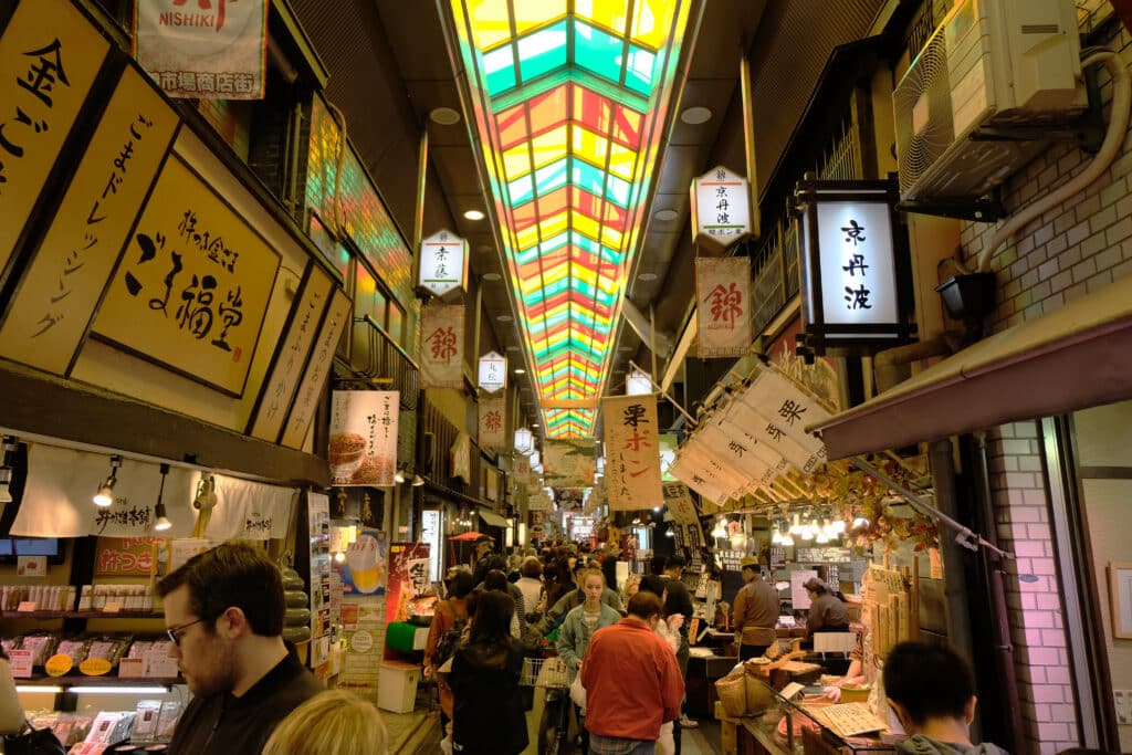 busy Nishiki Market in Kyoto with food stalls and colorful ceiling
