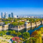 Aerial view of Osaka Castle surrounded by colorful autumn trees and city skyline