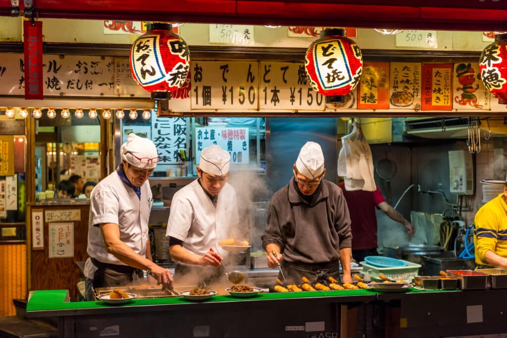 Street food vendors preparing takoyaki in Osaka at a traditional food stall