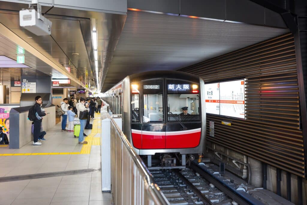 Osaka subway train arriving at Shin-Osaka Station platform with passengers waiting