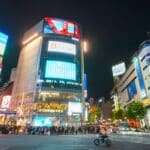 Shibuya street crossing at night with crowds and bright city lights in Tokyo