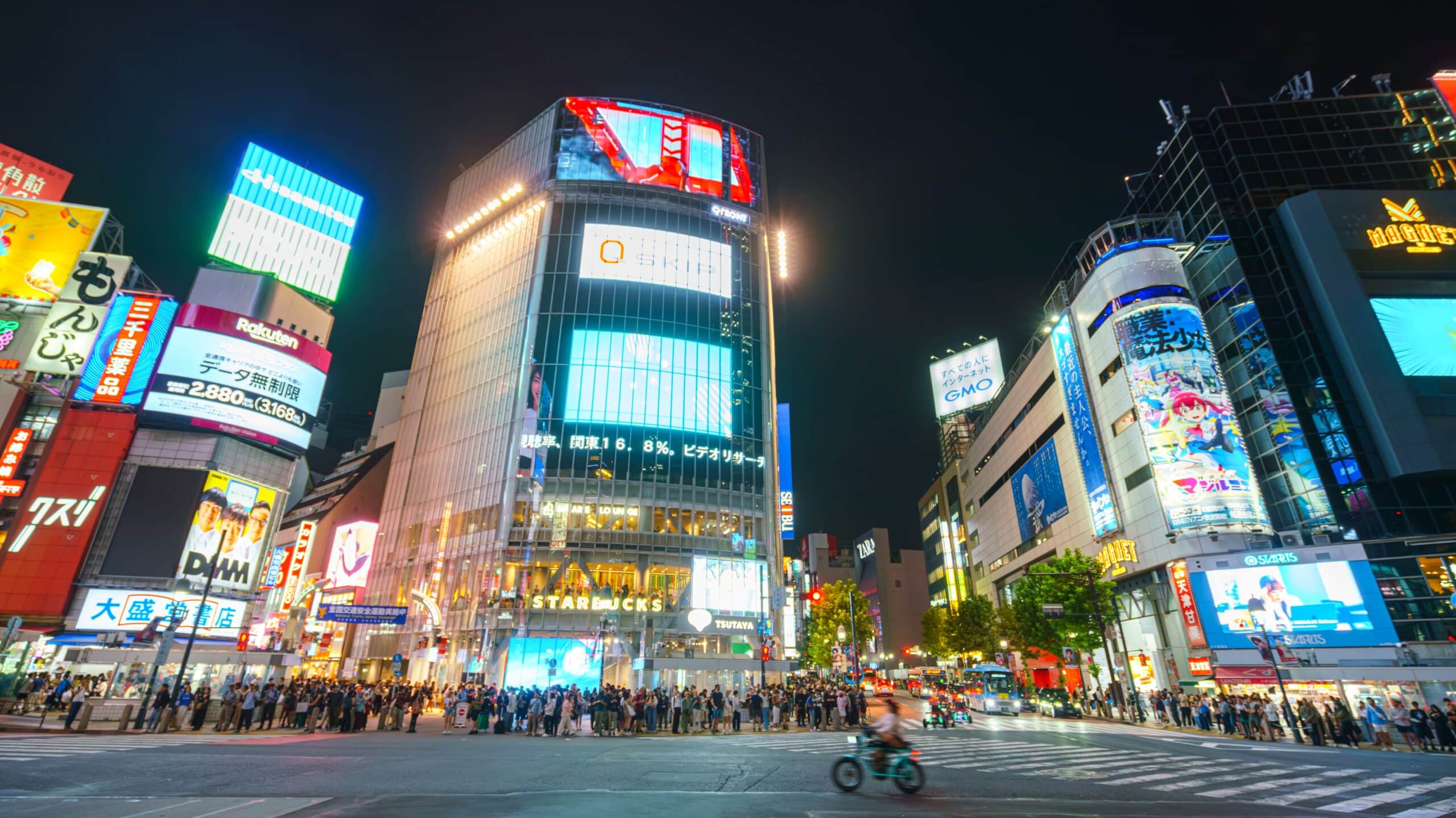 Shibuya street crossing at night with crowds and bright city lights in Tokyo