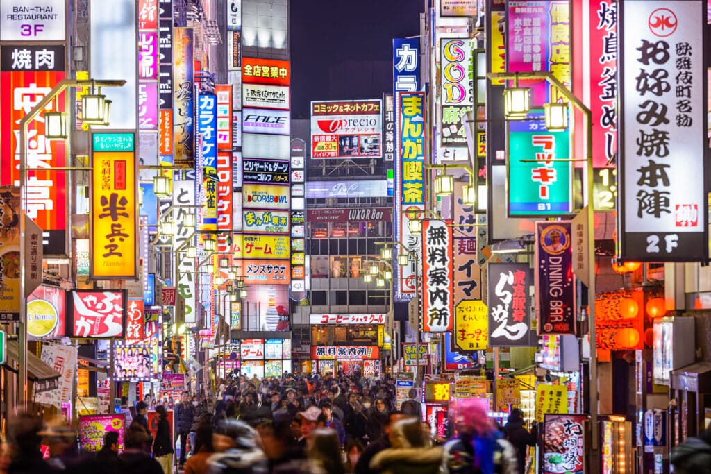 Neon-lit street in Shinjuku Tokyo at night with crowds