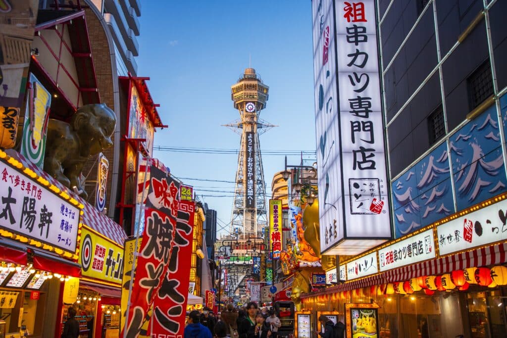 Shinsekai district street with Tsutenkaku Tower and colorful signs in Osaka