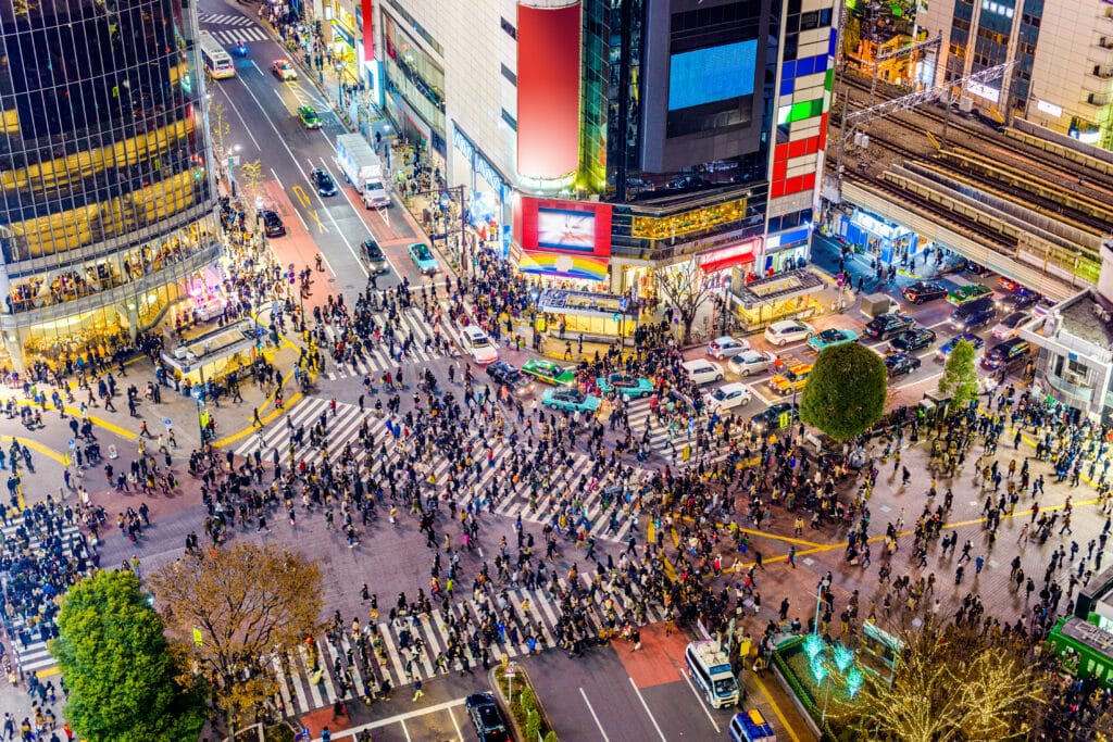 Aerial view of Shibuya Crossing at night with crowds crossing in all directions