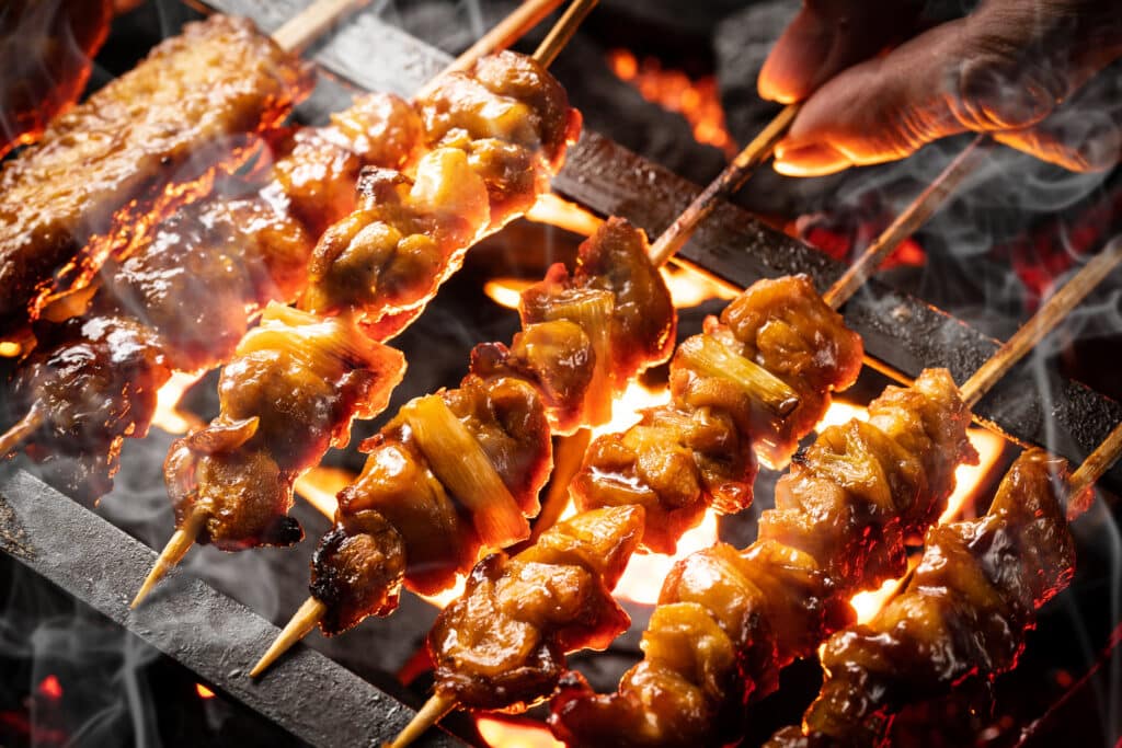 Yakitori chicken skewers grilling over charcoal in Japan