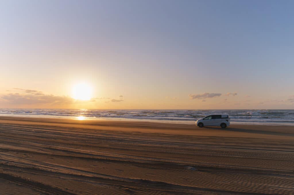 Car driving on Chirihama Beach sand in Ishikawa Japan at sunset