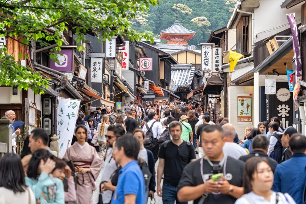 Crowds of tourists walking through Kyoto's historic Higashiyama district during the daytime