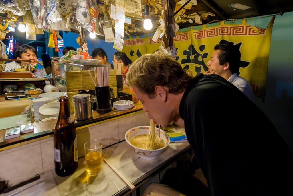 Visitor enjoying ramen at a traditional yatai food stall in Fukuoka