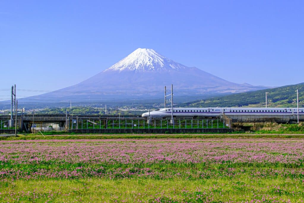 Shinkansen bullet train passing in front of Mount Fuji on a clear day in Japan