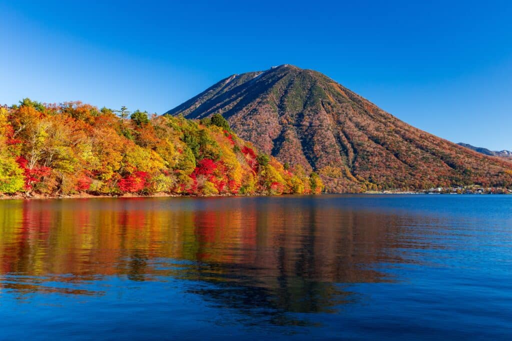 Lake Chuzenji surrounded by colorful autumn foliage in Nikko, Japan