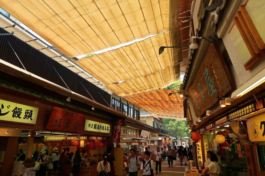 Visitors exploring Omotesando Shopping Street on Miyajima Island lined with food stalls and souvenir shops