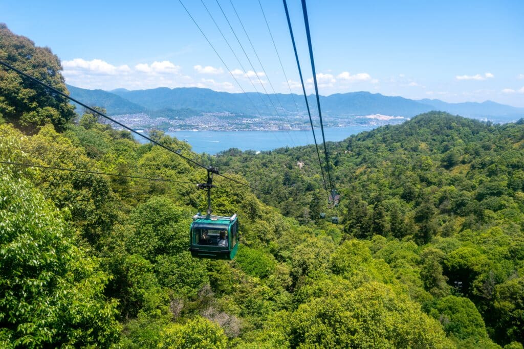 Miyajima Ropeway cabin traveling above forested slopes with views toward Hiroshima Bay