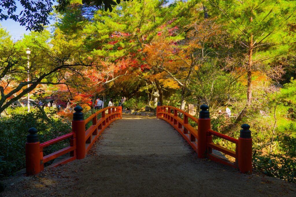 Red bridge surrounded by autumn maple trees in Momijidani Park on Miyajima Island