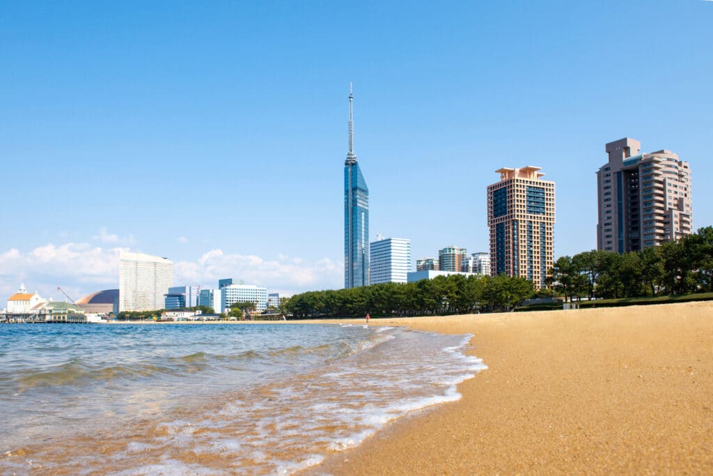 Sandy beach with Fukuoka Tower rising behind the waterfront skyline