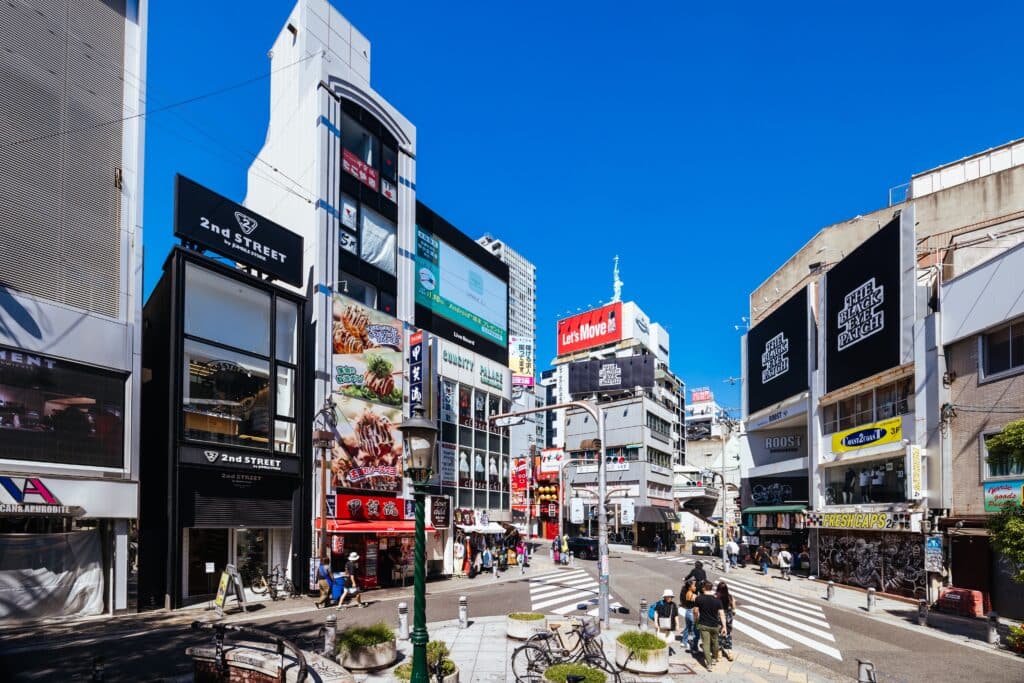 Amerikamura street in Osaka with shops, billboards, and pedestrians on a sunny day