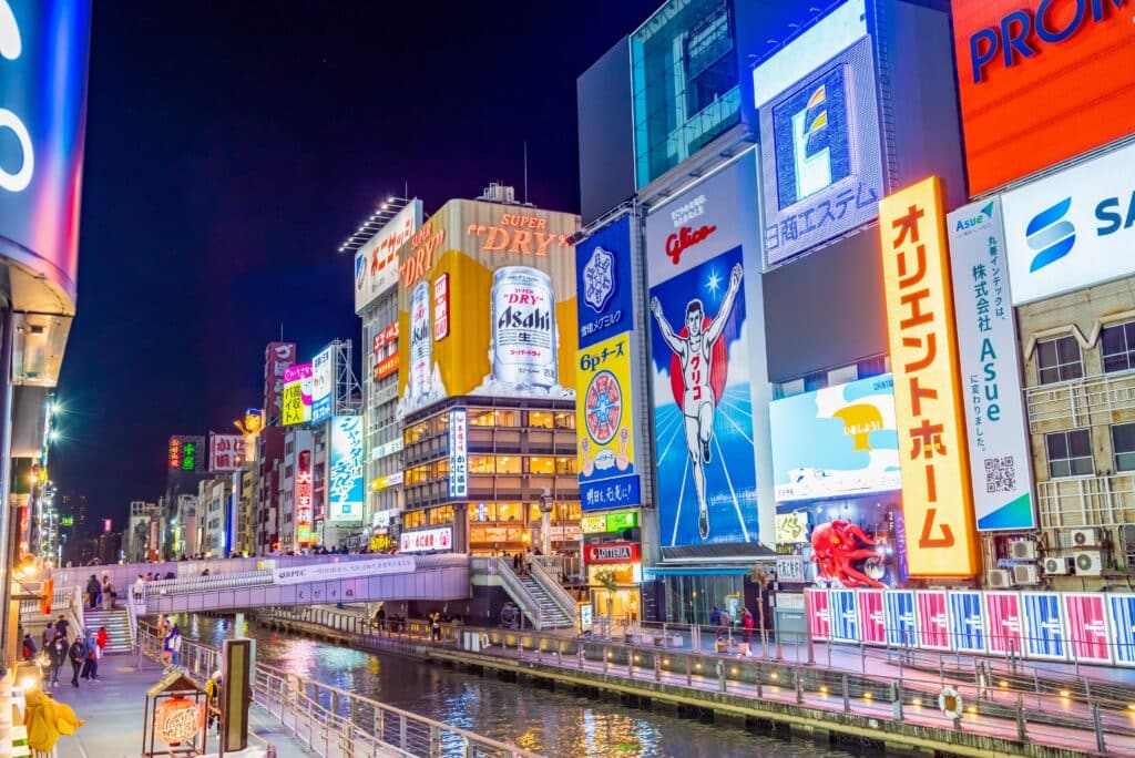 Dotonbori canal at night with bright neon lights and the famous Glico sign