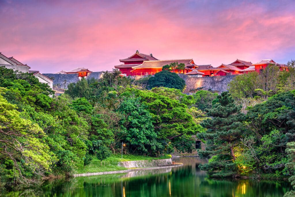 Shurijo Castle in Okinawa surrounded by tropical greenery at sunset