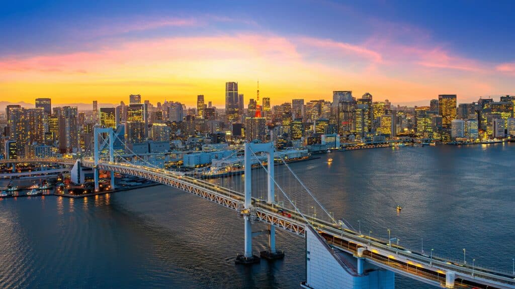 Tokyo skyline at sunset with Rainbow Bridge and illuminated city buildings