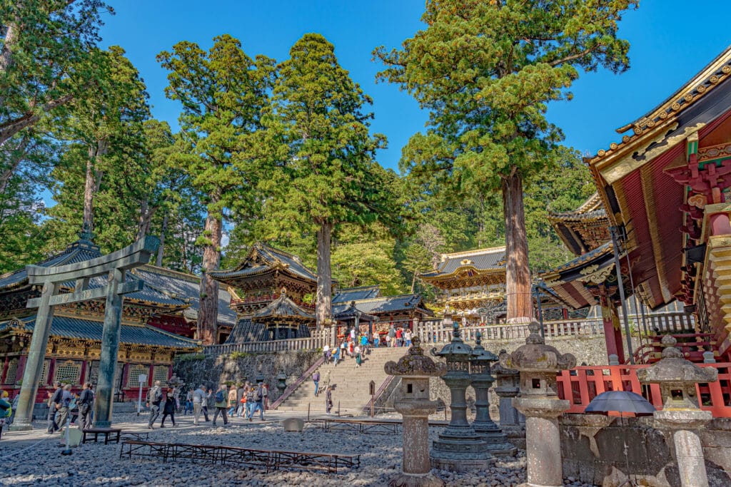 Visitors exploring the historic Toshogu Shrine complex surrounded by cedar trees in Nikko, Japan