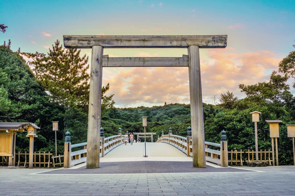 Large wooden torii gate and bridge leading toward Ise Grand Shrine surrounded by forest