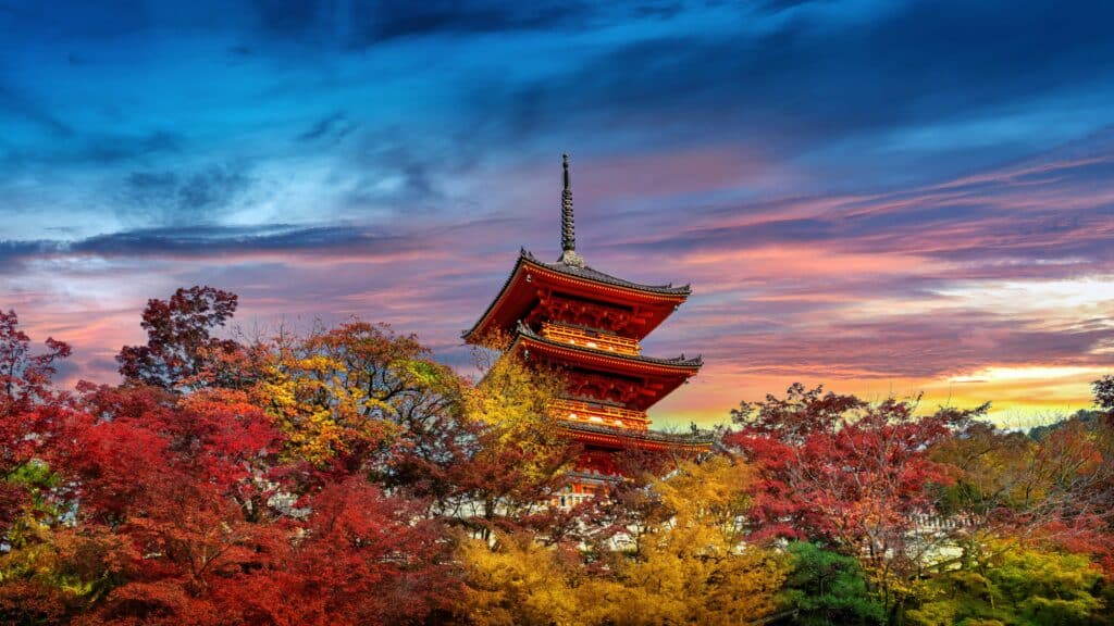 Historic Kyoto temple surrounded by colorful autumn foliage at sunset