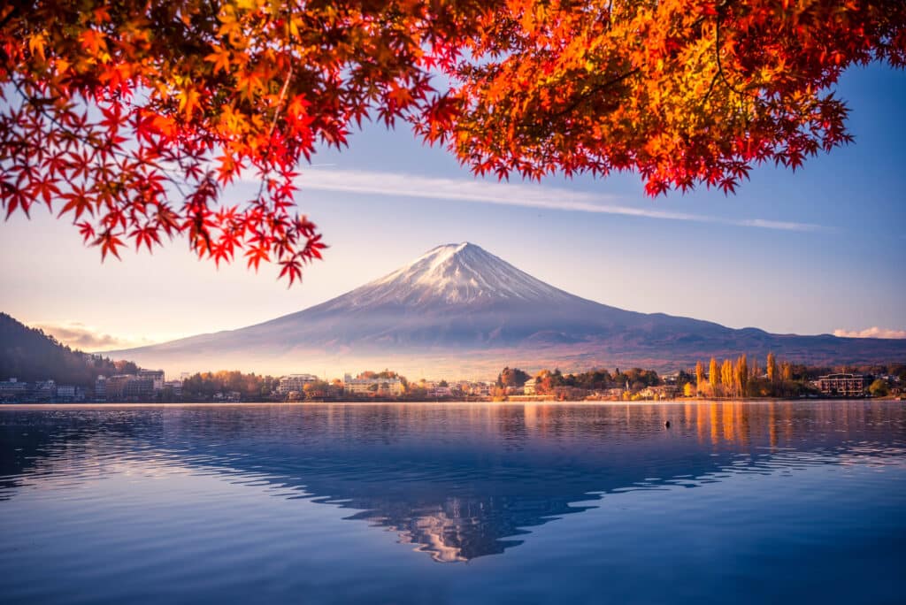 Mount Fuji framed by colorful autumn leaves along the shore of Lake Kawaguchi