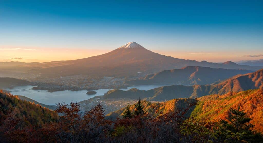 Panoramic view of Mount Fuji overlooking Lake Kawaguchi and autumn-colored mountains at sunset