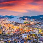 Panoramic sunset view over Nagasaki city and harbor from a hillside viewpoint with colorful evening sky