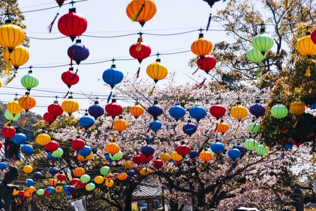 Colorful lanterns hanging above cherry blossom trees during a traditional festival in Nagasaki