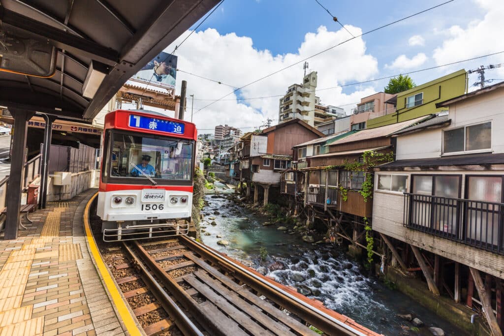 Nagasaki tram traveling through a traditional neighborhood beside a small river