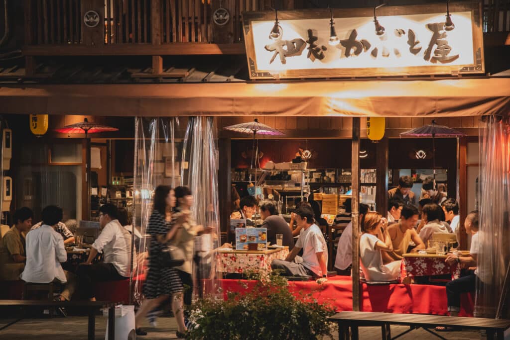 Traditional Japanese izakaya restaurant in Nagoya illuminated at night with diners enjoying local food and drinks