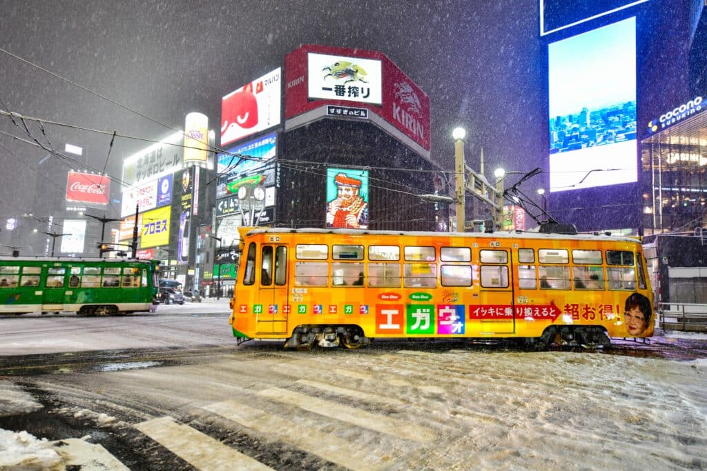 Traditional tram passing through snowy streets in Susukino during winter in Sapporo