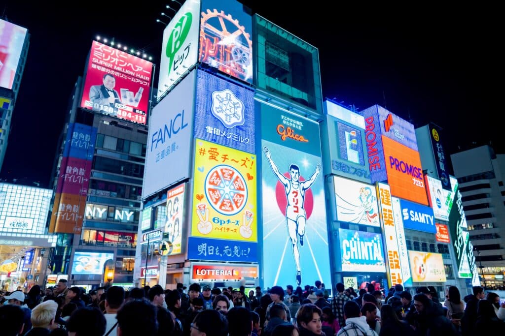 Crowds gathering beneath the famous Glico Running Man sign in Dotonbori