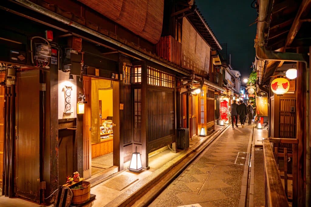 Traditional wooden buildings illuminated along a narrow street in Kyoto's Gion district