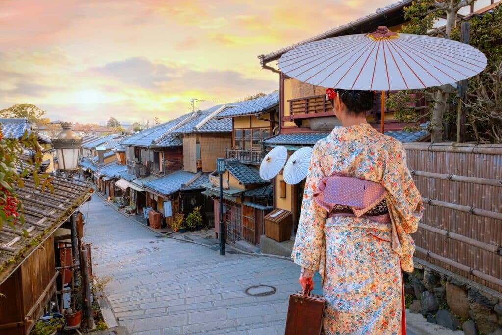 Woman wearing a traditional kimono overlooking Kyoto's Higashiyama district at sunset