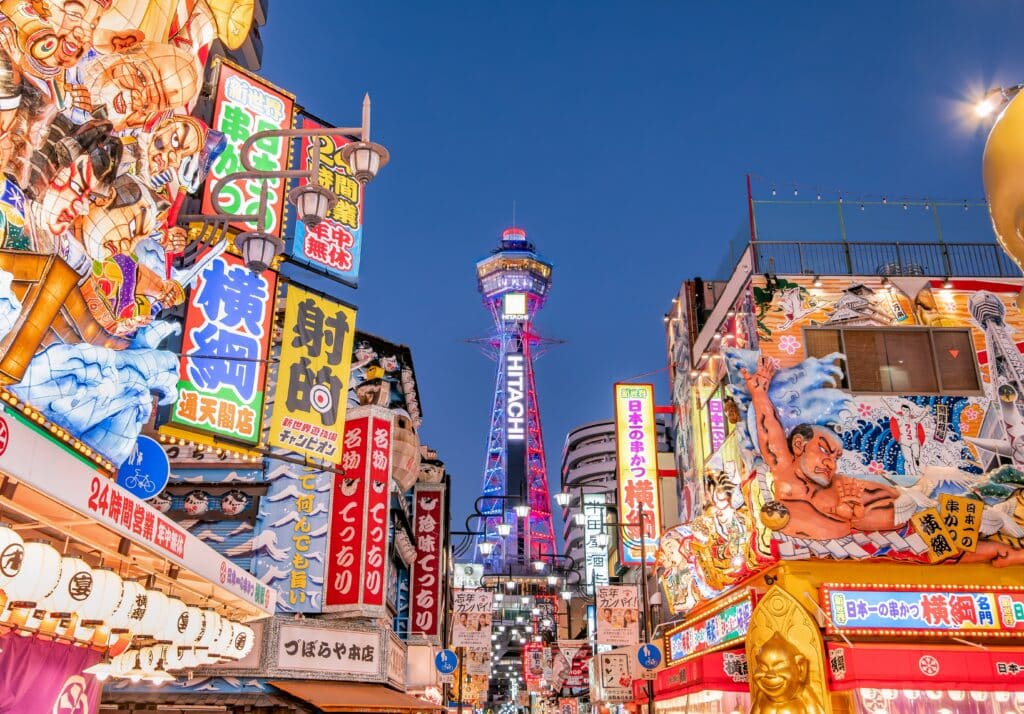 Colorful streets of Shinsekai with Tsutenkaku Tower illuminated at night