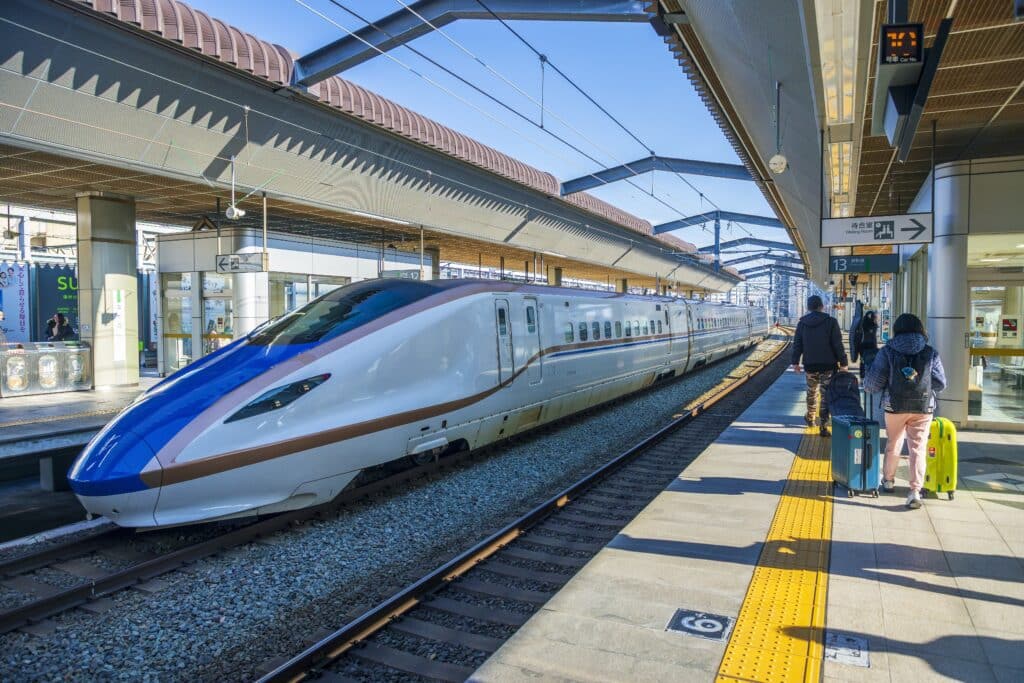 Hokuriku Shinkansen with travelers on a station platform in Japan