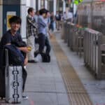 Travelers with luggage waiting for a train at a railway station in Japan