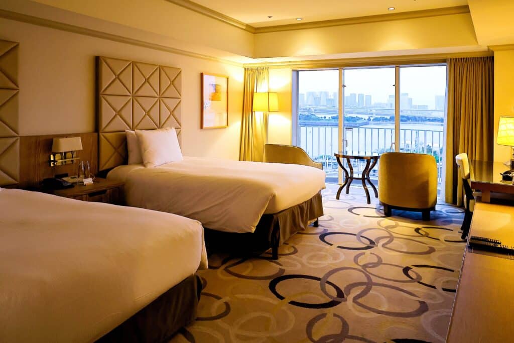 Twin hotel room in Japan with beds, seating area and city view