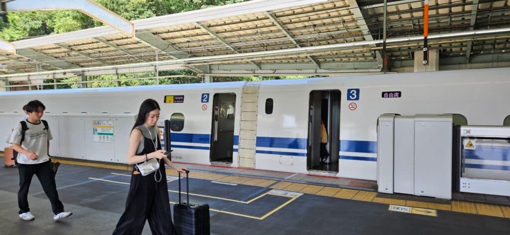Travelers with luggage beside a Shinkansen bullet train in Japan