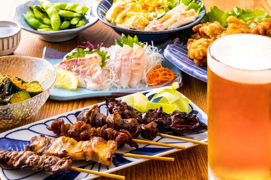 Japanese izakaya meal with sashimi, yakitori, side dishes and beer